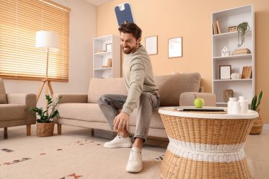 Kızgın genç adam evde tartıları kırıyor.