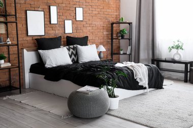 Konforlu yatağı, siyah çarşafları ve raf ünitesi olan modern yatak odası.