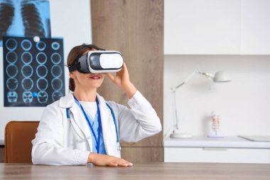 Klinikteki masada VR gözlüğü kullanan kadın doktor.