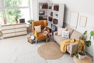 Kahverengi koltuğu, gri kanepesi ve kitaplığı olan şık bir oturma odası.