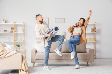 Evde mikrofonlu ve teypli genç çift dans ediyor.