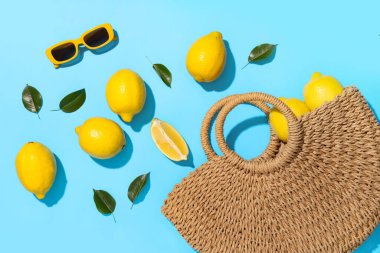 Taze limonlu hasır çanta ve mavi arka planda şık güneş gözlükleri.