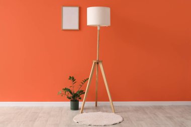 Turuncu duvarın yanında çiçekli standart lamba.