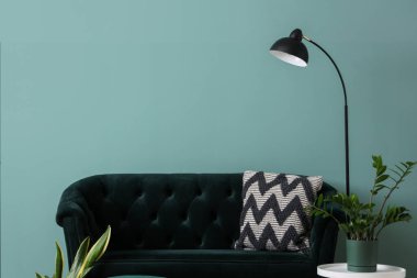 Yeşil kanepesi, kahve masası, puf ve çiçekleri olan şık bir oturma odası.