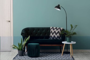 Yeşil kanepesi, kahve masası, puf ve çiçekleri olan şık bir oturma odası.