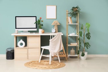 Modern bilgisayarla rahat çalışma alanı, raf ünitesi ve mavi duvarın yanındaki ev bitkileri