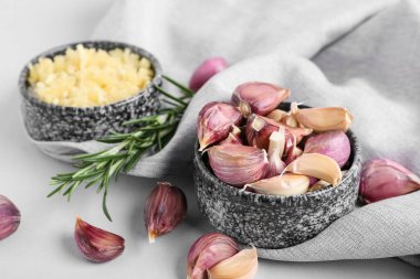 Taze sarımsak karanfilli kase ve gri arka planda biberiye, yakın plan.