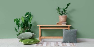 Yeşil duvarın yanında çiçekli ve yastıklı bir bank.