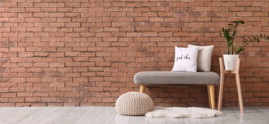 Odadaki tuğla duvarın yanında yumuşak bir bank ve puf.