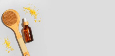 Gerekli yağ, masaj fırçası ve gri arka planda deniz tuzu şişesi.