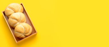 Lezzetli Kayzer sarı arkaplanda ahşap kutuda yuvarlanıyor.