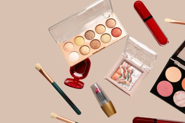 Bej arka planda uçan dekoratif kozmetik ürünleri