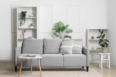 Kanepe, masa ve raf üniteleriyle aydınlık oturma odasının içinde.