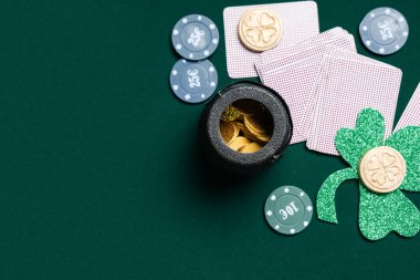 Poker fişleri, kartlar, yoncalar ve koyu yeşil arka planda bozuk paralar. Aziz Patrick Günü kutlaması