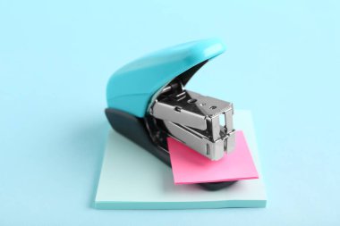 Renk arkaplanı üzerine yapışkan notları olan mavi zımba.