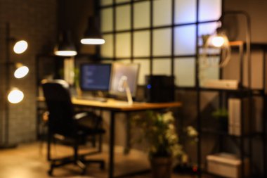 Programcının iş yeri ve gece lambasıyla karanlık ofisin bulanık görüntüsü