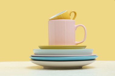 Sarı arkaplana karşı masada temiz bardak ve tabaklar