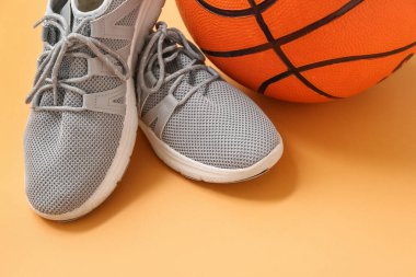 Basketbol ve gri spor ayakkabıları turuncu arka planda, yakın plan