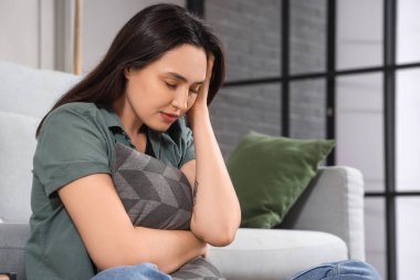 Evde yastıklı depresif genç bir kadın.