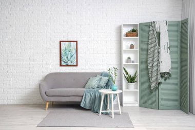 Rahat kanepesi, raf ünitesi ve katlanır ekranı olan modern bir oda.