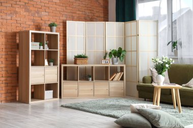 Katlanır ekran, kanepe ve raf ünitesi olan şık bir oturma odası.