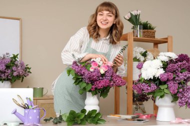 Çiçekçide leylaklarla güzel çiçek yapan kadın çiçekçi.