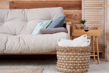 Rahat kanepe, rattan sepet ve sehpası olan şık bir oturma odası.