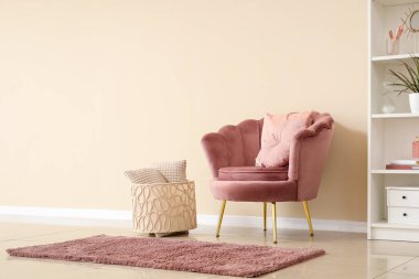 Pembe koltuklu, minderli, sepetli ve raflı oturma odasının içi.