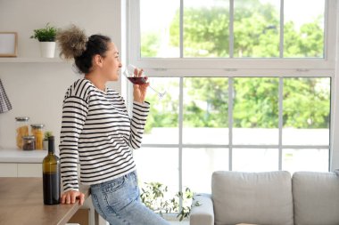 Evinde şişe ve bir bardak kırmızı şarapla orta yaşlı güzel bir kadın.