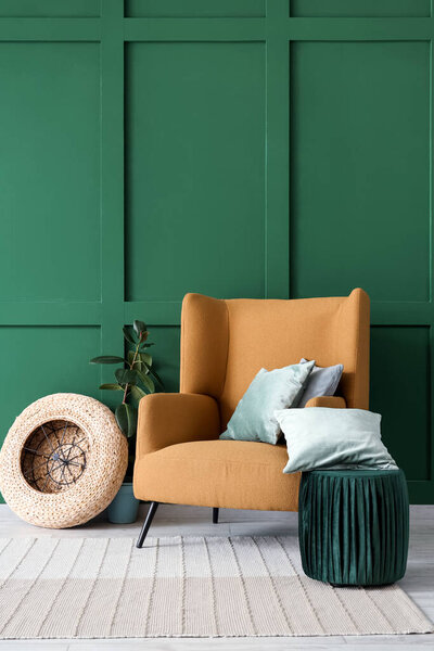 Interior of living room with brown armchair, houseplant, cushions and pouf