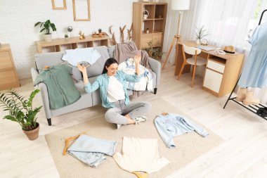 Şık elbiseli genç bir kadın evde oturuyor.