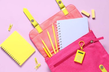Okul çantası ve pembe arka planda farklı kırtasiye malzemeleri.
