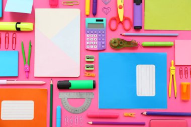 Pembe arka planda not defterleri ve kırtasiye malzemeleri