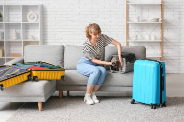 Evcil hayvan taşıyıcısı ve evdeki kanepede oturan sevimli kedili genç bir kadın.