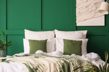 Yatak odasının içinde büyük rahat bir yatak, lamba ve bitkiler var.