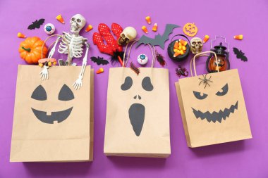 Renkli arka planda Cadılar Bayramı için kağıt alışveriş torbaları, tatlılar ve dekorasyonlar içeren kompozisyon