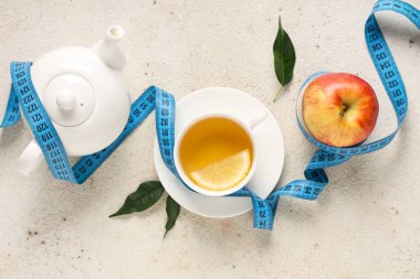 Bir fincan diyet çayı, mezura, elma ve çaydanlık. Kilo verme konsepti