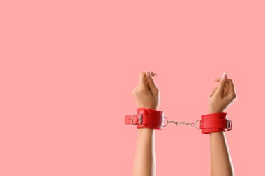 Pembe arka planda seks dükkanından kırmızı kelepçeli bir kadın.