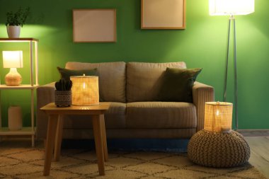 Konforlu kanepe, kahve masası ve oturma odasının içinde parlayan lambalar.