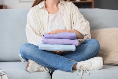 Evdeki kanepede oturan temiz elbiseli genç bir kadın.