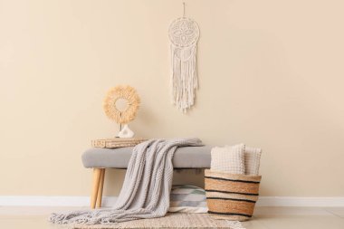 Saf battaniyeli gri bank, bej duvarın yanında kitaplar ve sepet.