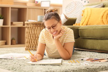 Genç bayan sanatçı yerde yatıyor ve çizim yapıyor.