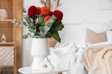 Süslü yatak odasının içindeki kahve masasının üstünde vazodaki Dahlia çiçekleri.