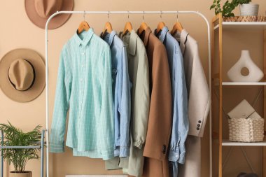 Bej duvarın yanında giysi askılığı ve raf ünitesi olan modern giyinme odasının içinde, yakın plan.