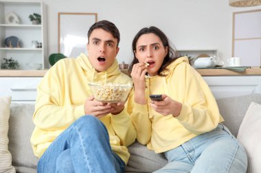 Evde taze patlamış mısırlı korkmuş bir çift film izliyor.