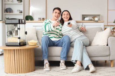 Modern patlamış mısır makinesi olan sevimli bir çift evde film izliyor.