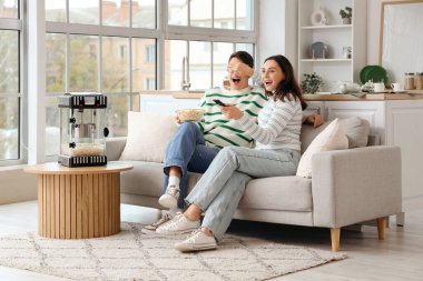 Modern patlamış mısır makinesi olan sevimli bir çift evde film izliyor.