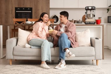 Kanepede oturan patlamış mısırlı tatlı çift.