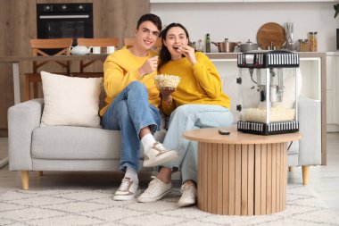 Modern patlamış mısır makinesi olan sevimli bir çift evde film izliyor.