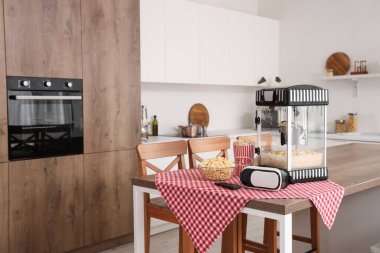 Modern patlamış mısır makinesi ve VR gözlükleri mutfaktaki masada.